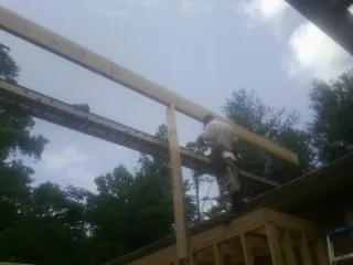 Carpenter setting a ridge beam over a new addition frame — Ice Dam Removal by Roofing Brothers in New Bedford