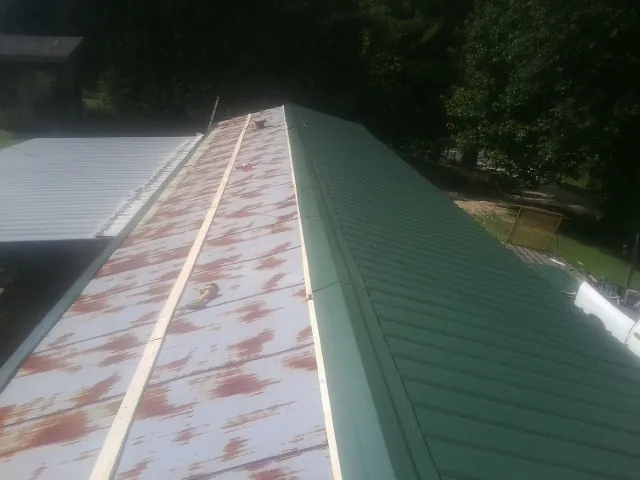 Old rusted panels beside newly installed green metal roofing — Wind Damage Roof Repair by Roofing Brothers in New Bedford