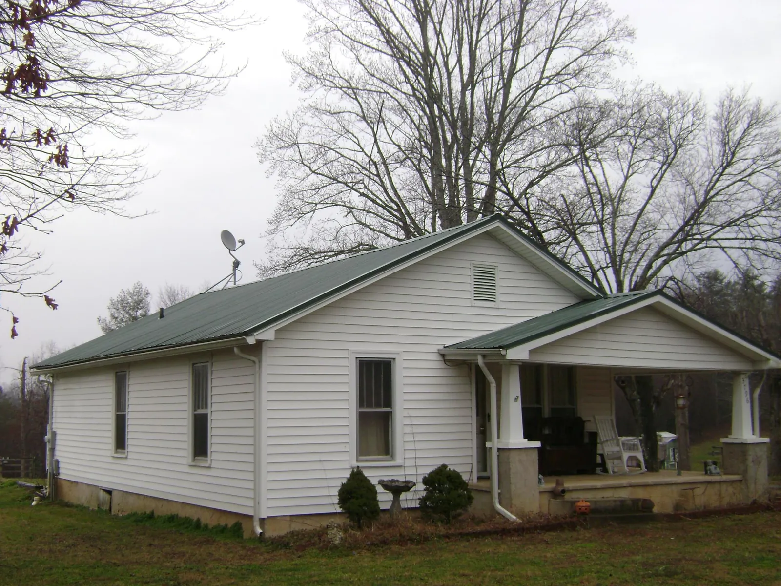 Green metal roof on a white bungalow with a side porch in New Bedford